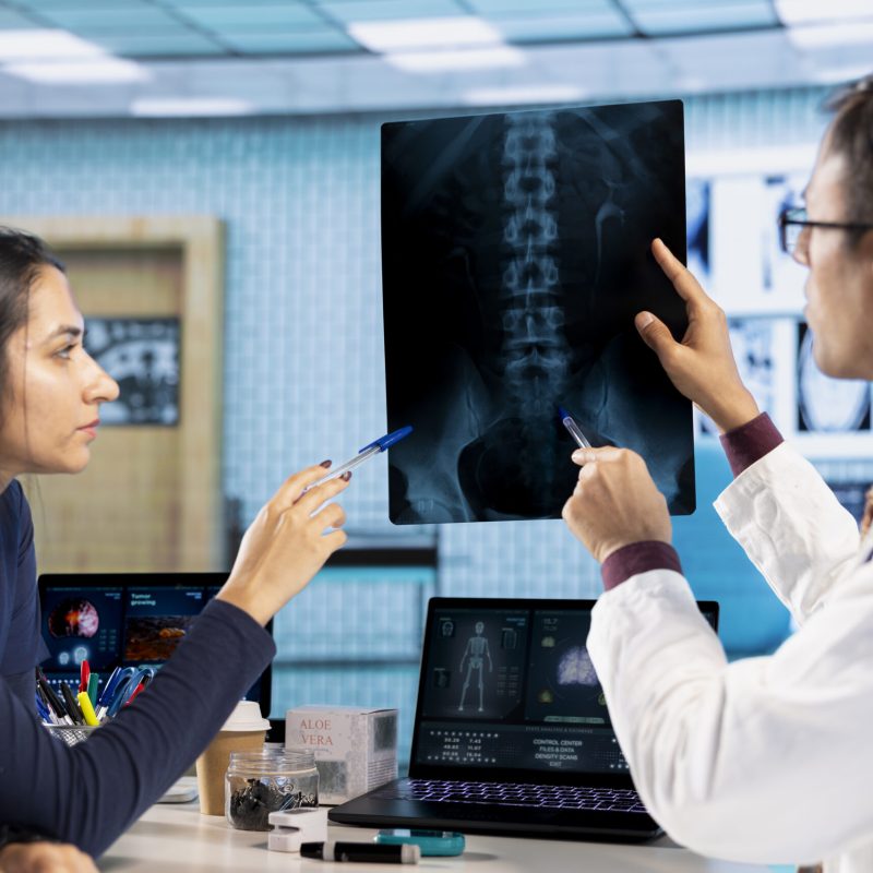Indian healthcare professional sharing medical expertise with a patient in office, examining x ray and MRI scans results and focusing on disease recovery. Diagnostic report in a meeting.