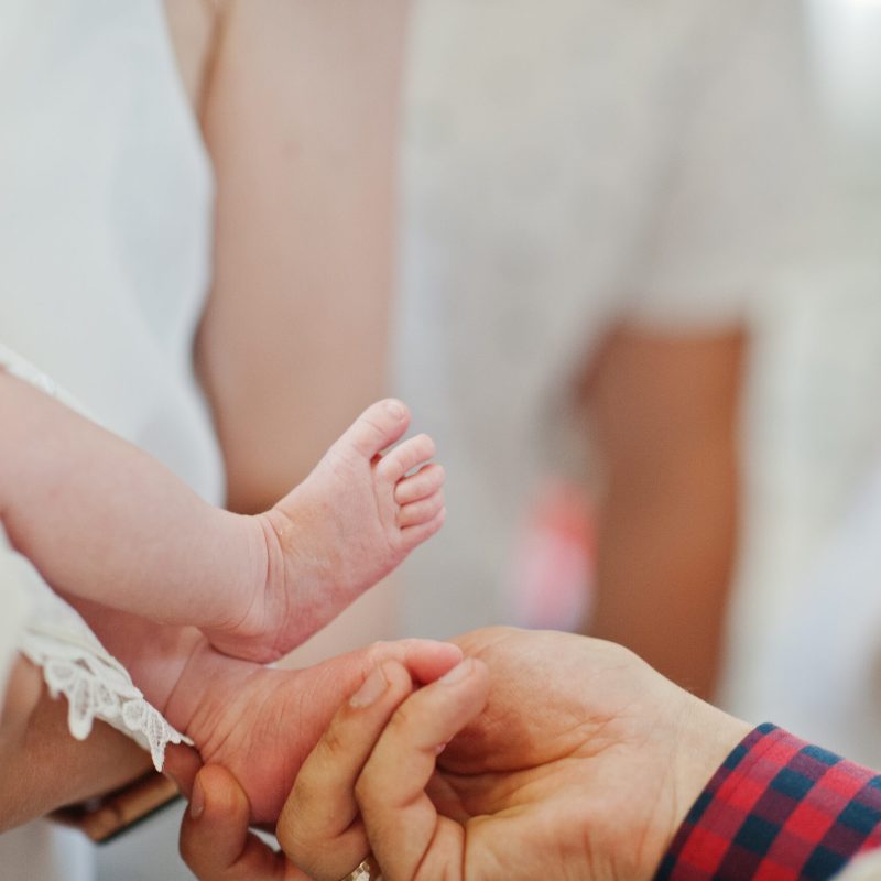 Legs of newborn baby at baptism ceremony in church.